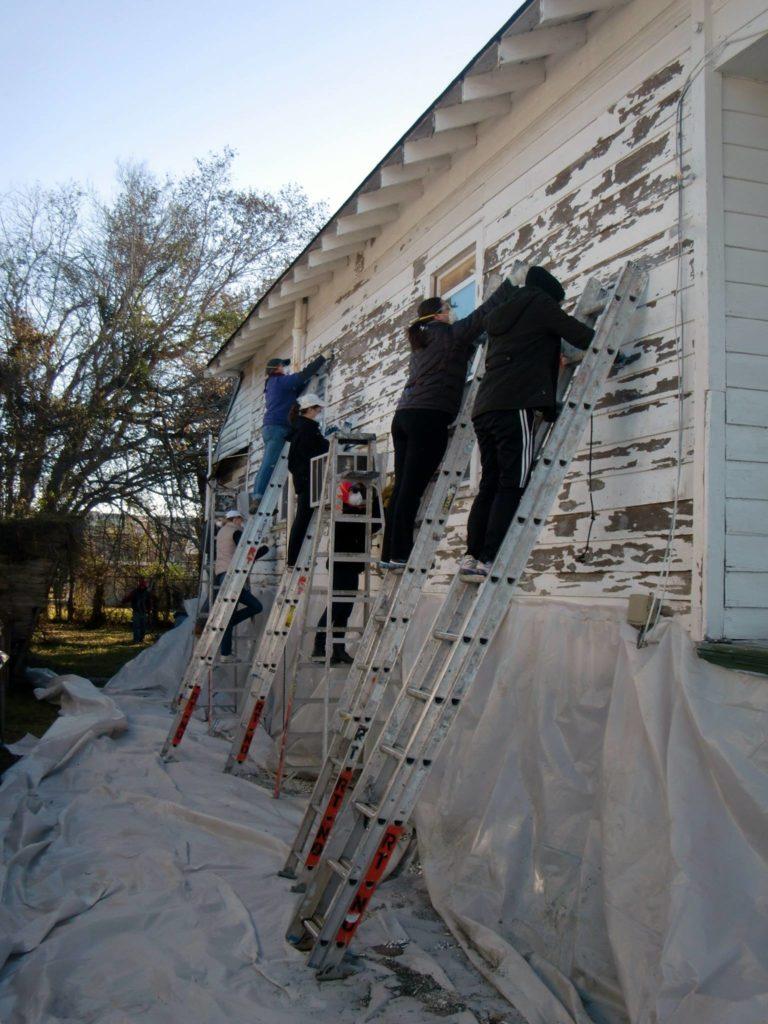 Students on ladders restore a home in New Orleans