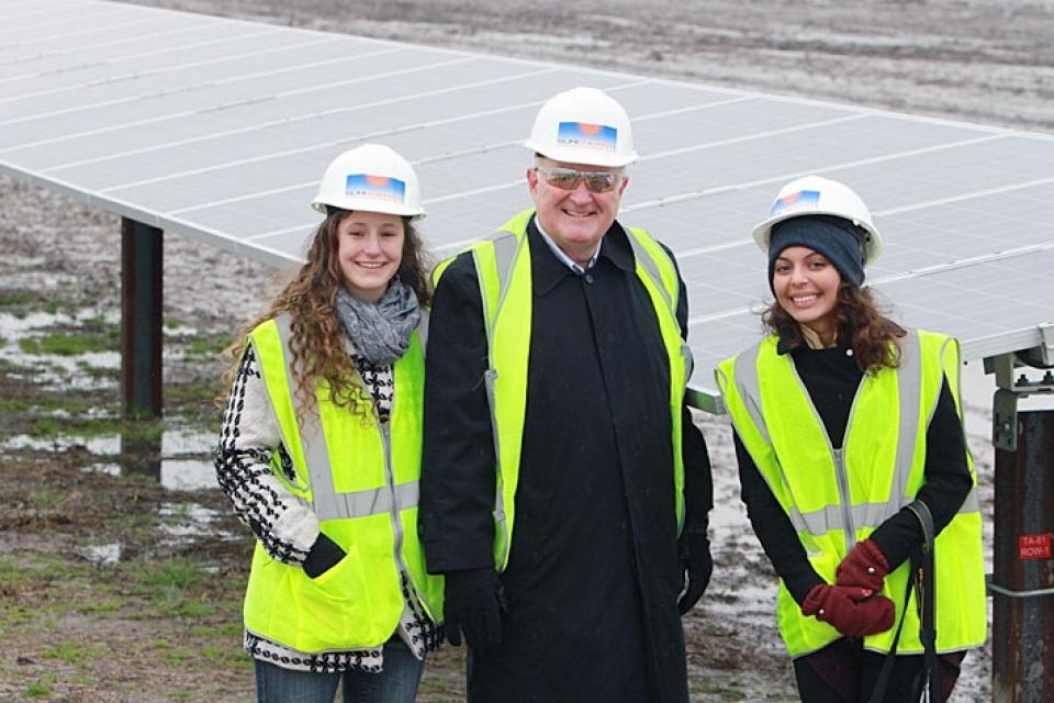 University President Steven Knapp poses with  Eleanor Davis and Zorah Roy at a solar power farm in North Carolina. Photo courtesy of GW Media Relations.