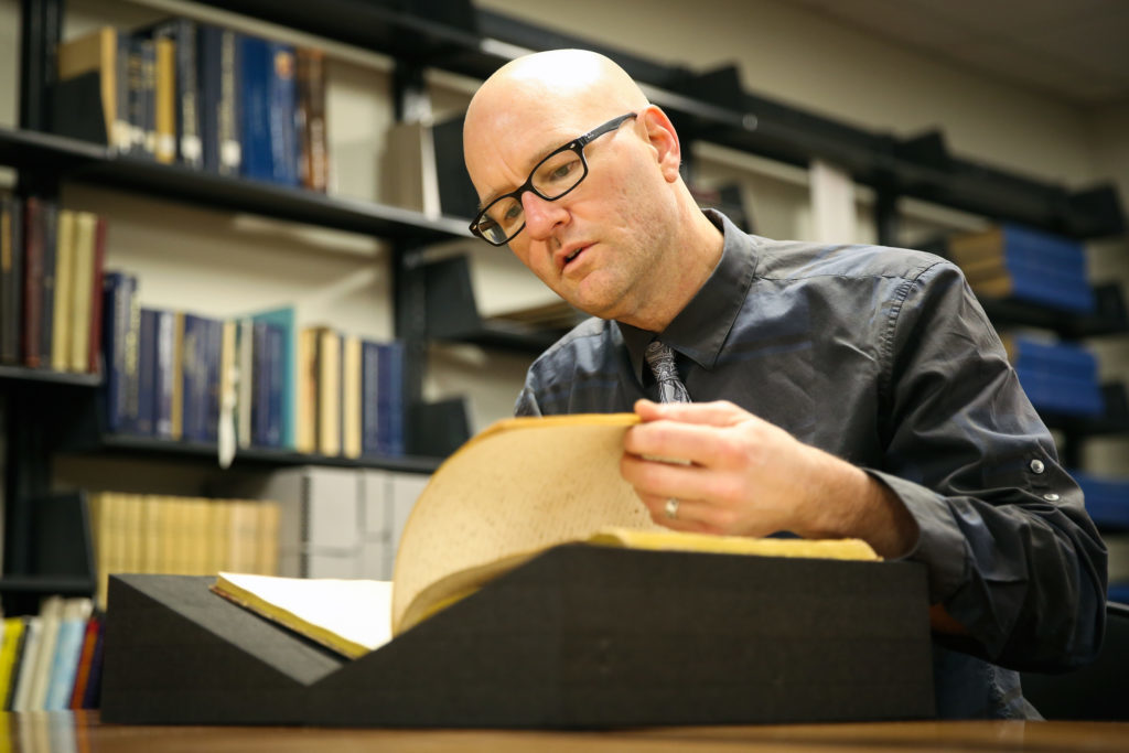Phillip Troutman, an assistant professor of writing and history, reads the diary of Jonathan Tilson who graduated in 1848. He is one of the faculty members researching GWs history with slavery.