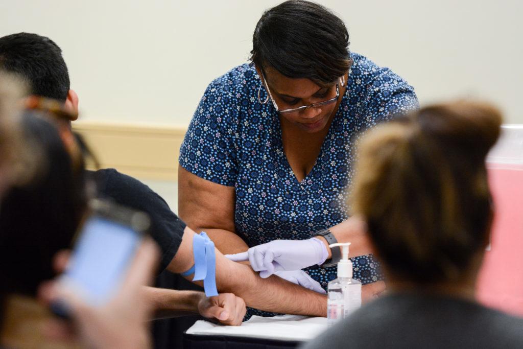 Sylvia Pearson, who works for HBI-DC, tests a student for hepatitis B, hepatitis C and HIV infections at the event Tuesday night.