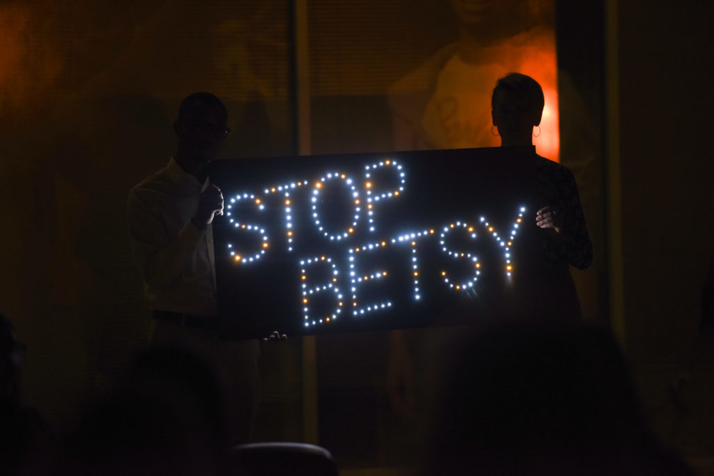 A demonstrator holds a light-up sign condemning Education Secretary Betsy DeVos stance on Title IX enforcement during a candlelight vigil Thursday outside the Department of Education.