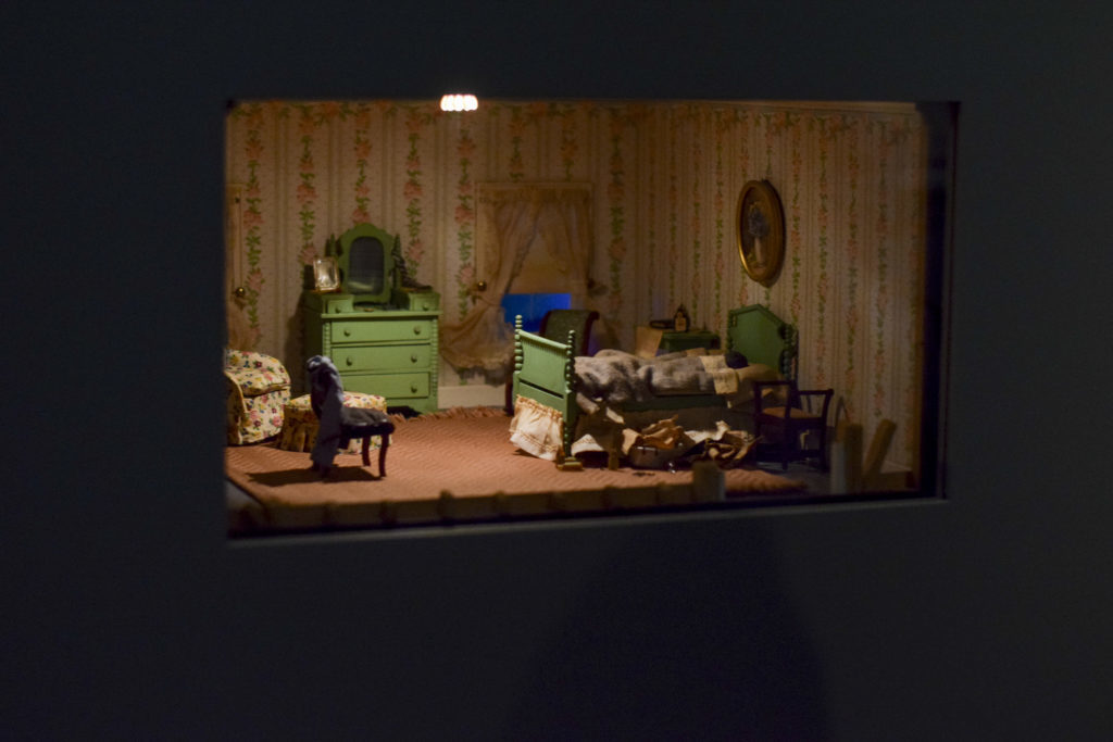 The exhibit features a series of sharply and carefully detailed dollhouse-sized crime scenes. The scenes blur the line between forensics and art with extremely intricate detail in their design but resemble real crime scenes.