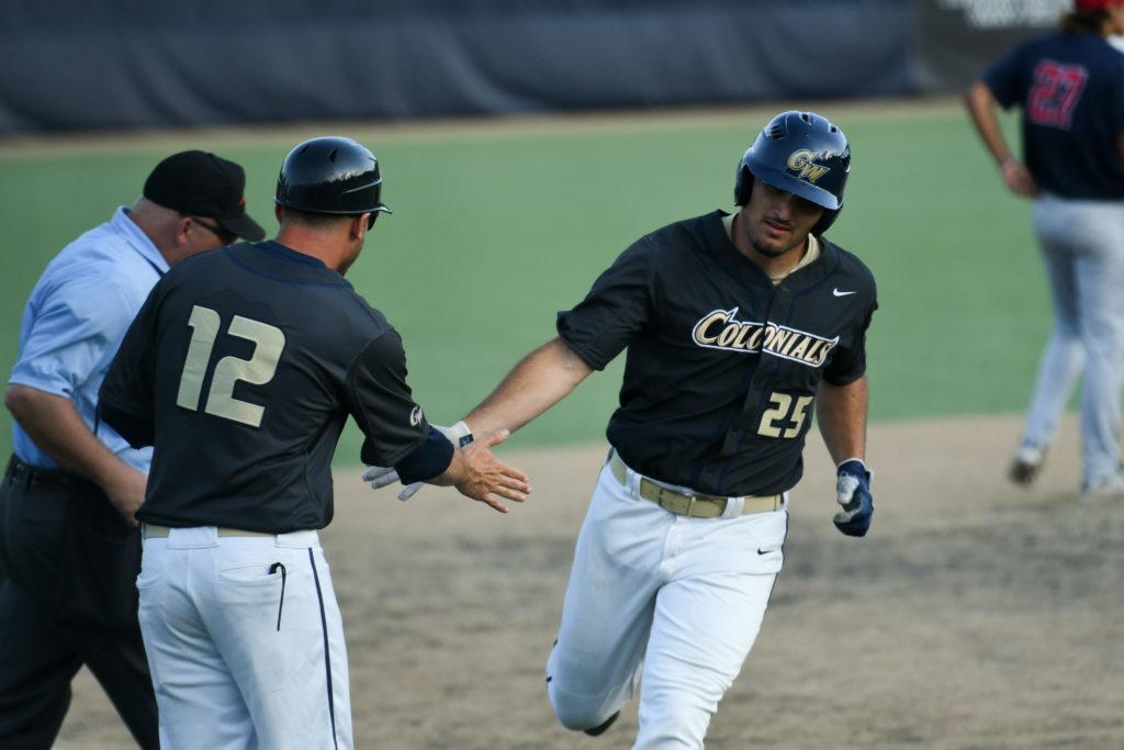 Junior Dominic DAlessandro rounds home plate and high fives assistant coach Dave Lorber after a home run in the Colonials first game of the day Friday.