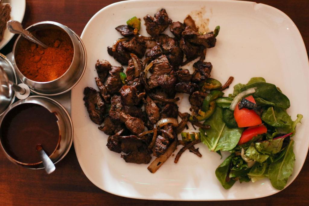 The beef special tibs ($14.99, $18.50 for large) is presented with three different spice canisters and a side salad.