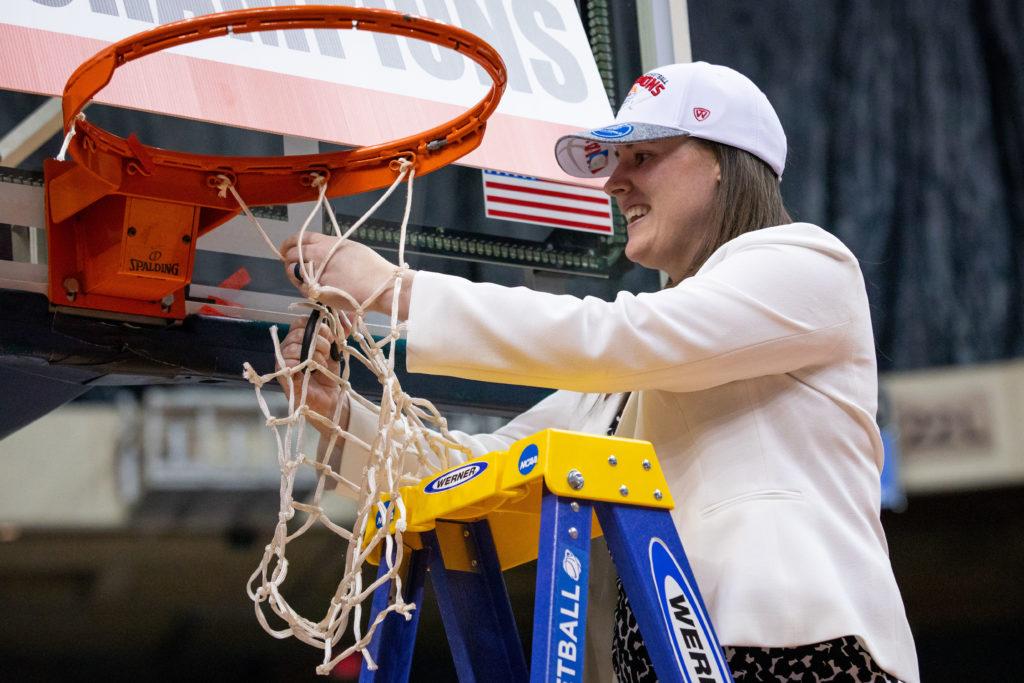 Womens basketball assistant coach Jackie Smith cuts off a piece of the net after the team won the Atlantic 10 Championship this year.