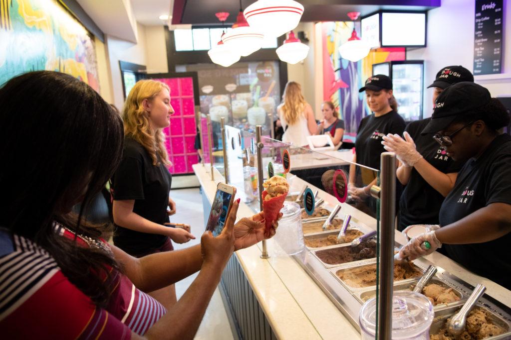 A customer snaps a photo of a scoop of cookie dough at The Dough Jar, which will officially open Saturday.