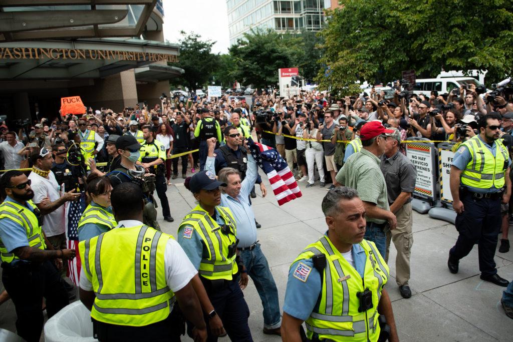Demonstrators participating in the Unite the Right 2 rally exit the Foggy Bottom Metro Station surrounded by law enforcement officers Sunday.