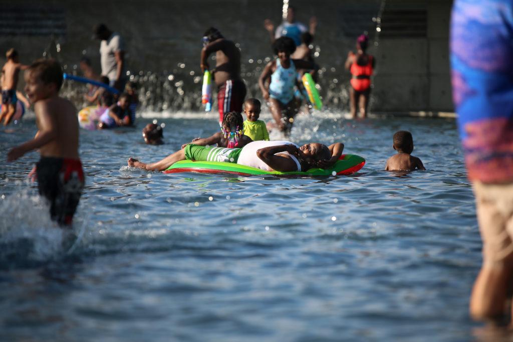 Children and adults escape the summer heat in a fountain at Yards Park. 