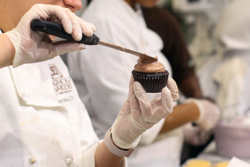 An employee frosts a chocolate cupcake at Magnolia Bakery's new location at Union Station.