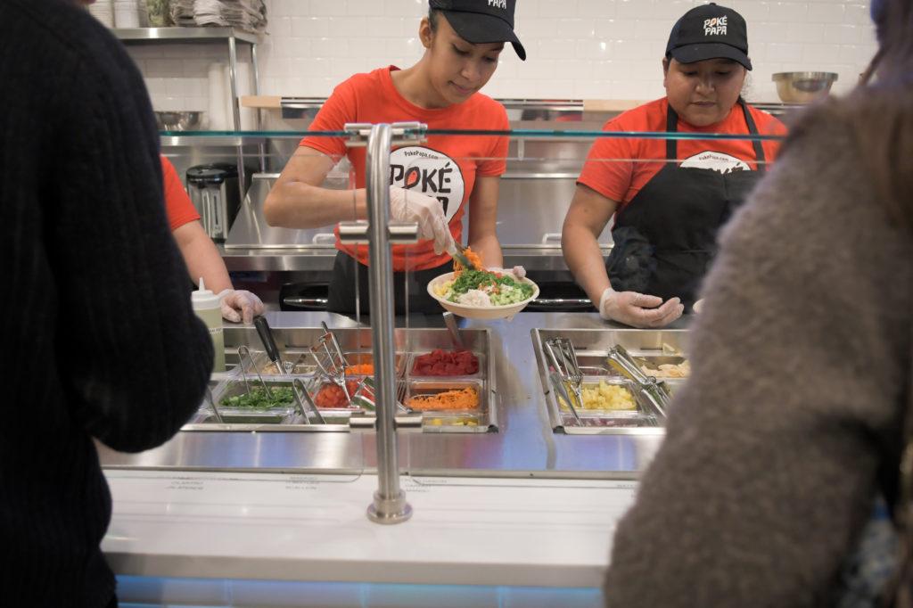 Workers assemble poke bowls at Poke Papa last Monday during the soft opening of its new location at 1919 Pennsylvania Ave. NW. 