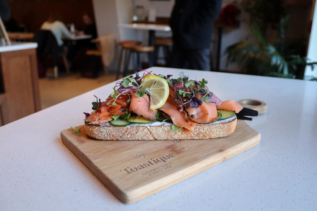 The smoked salmon toast ($14) begins with a slice of sourdough toast smeared with herb cream cheese and piled high with sliced cucumbers, microgreens, pickled red onions and a lemon.