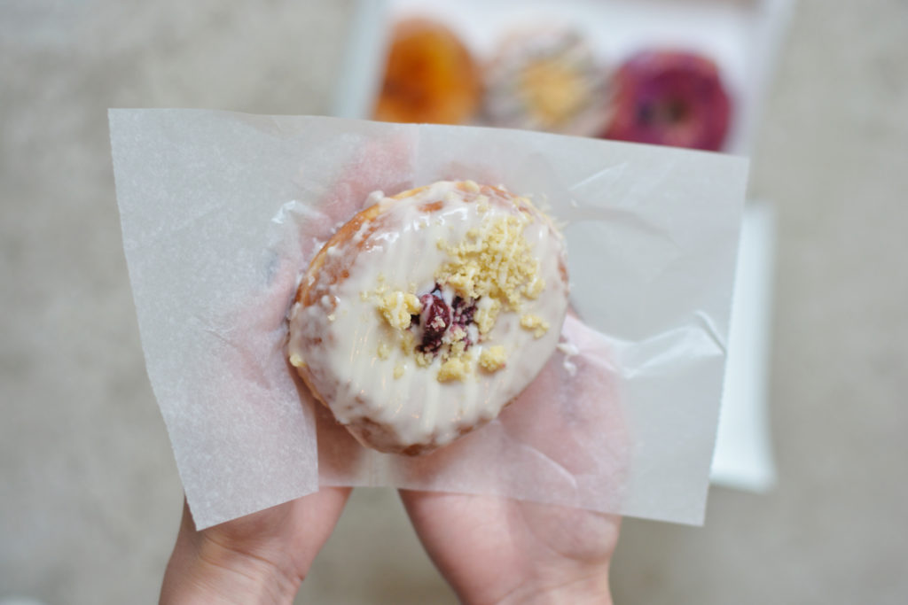 District Doughnut's cherry blossom doughnut is topped with a sweet cherry in its center and a pie crust crumble. 