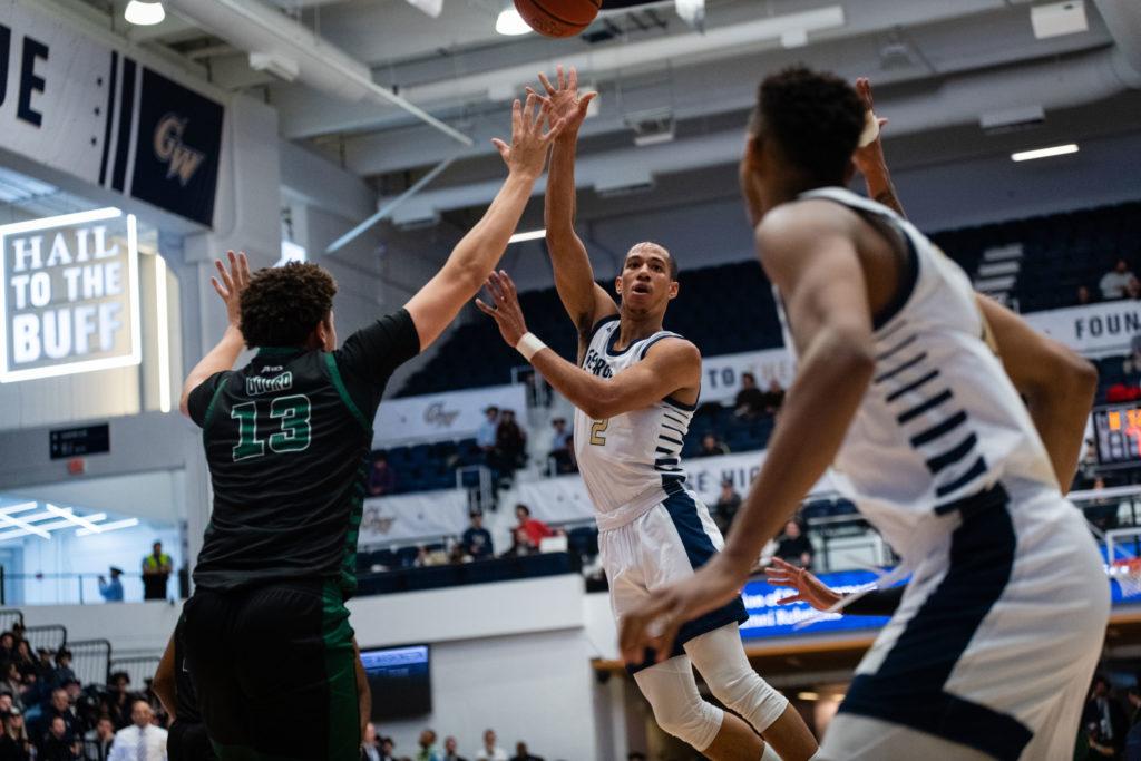 Redshirt senior guard Armel Potter dishes a pass to junior forward Ace Stallings in a game against George Mason Wednesday. The Colonials routed the Patriots 73–67.