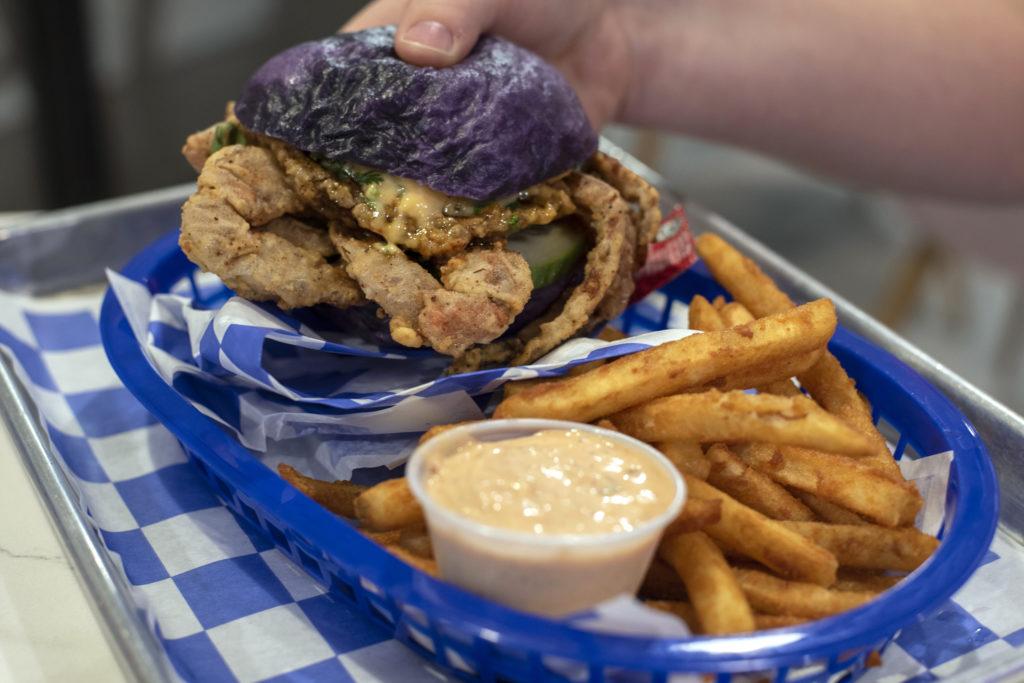 With a vibrant purple bun and fried crab legs sticking out from all sides, the sandwich looks like something out of a cartoon.