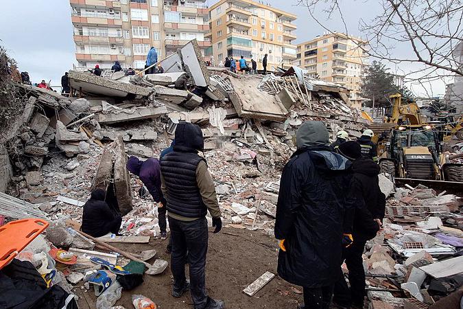 Onlookers gaze upon a mound of rubble, the result of a 7.8-magnitude earthquake that devastated Turkey Monday, killing more than 34,000 to date. 