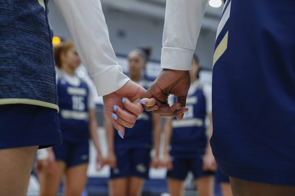 (L-R) Natalia Sierra-Vargas and Jayla Thornton interlock their pinky fingers as they stand in a team huddle.  