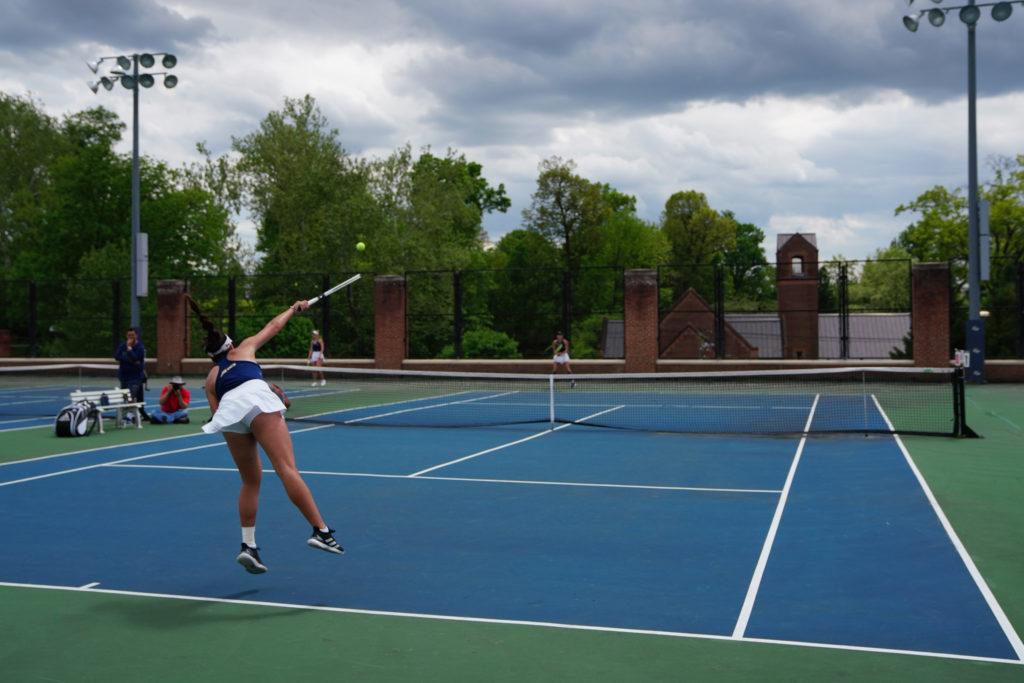 A women’s tennis player delivers an overhead shot.