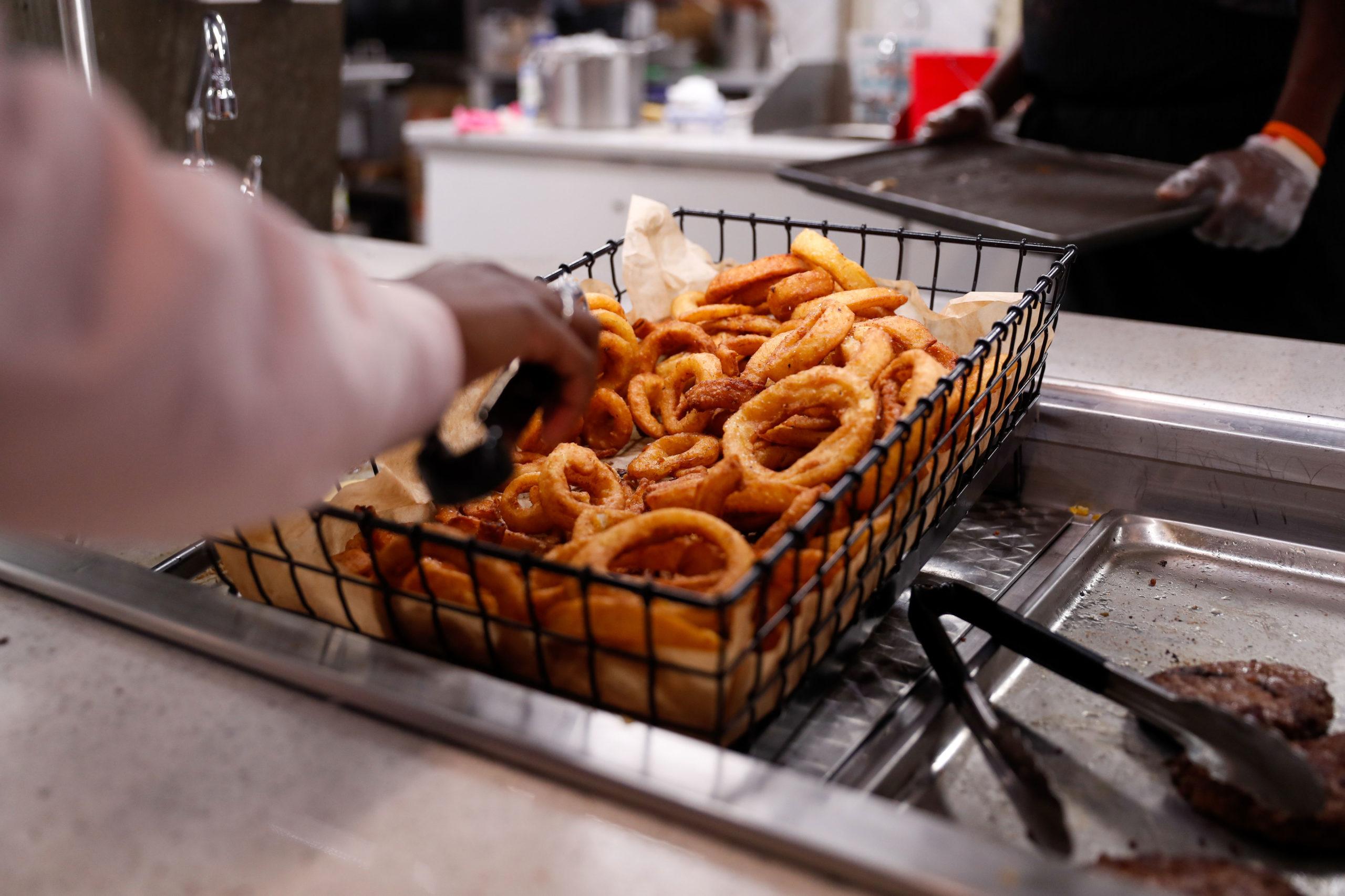 A student scoops up a fresh batch of onion rings at Shenkman Dining Hall.
