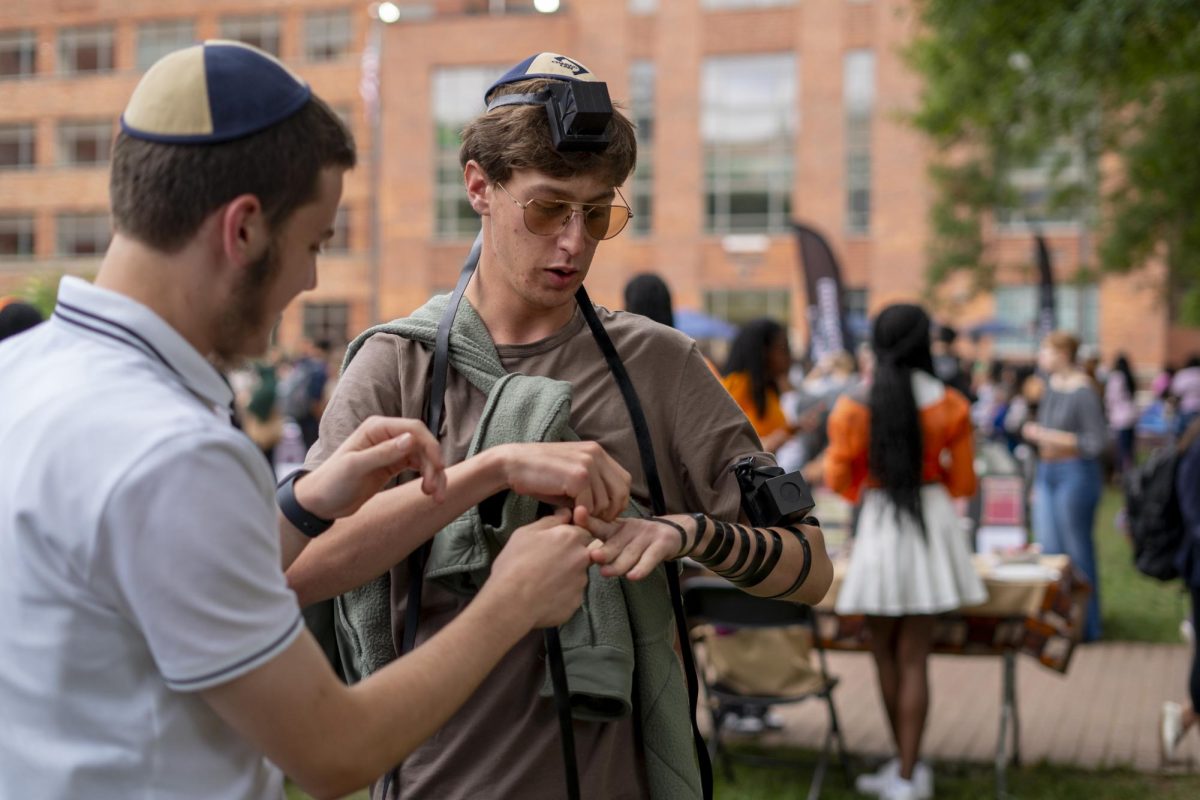 Two students wrap tefillin, a Jewish practice of strapping black leather boxes containing Hebrew scrolls to ones head and arm to bring oneself closer to God during prayer.