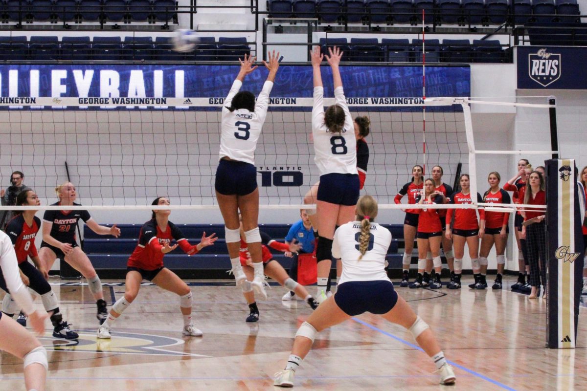 Graduate student Kelsey Watkins and sophomore setter Maeve Loughran leap to block a spike during a match against Dayton.