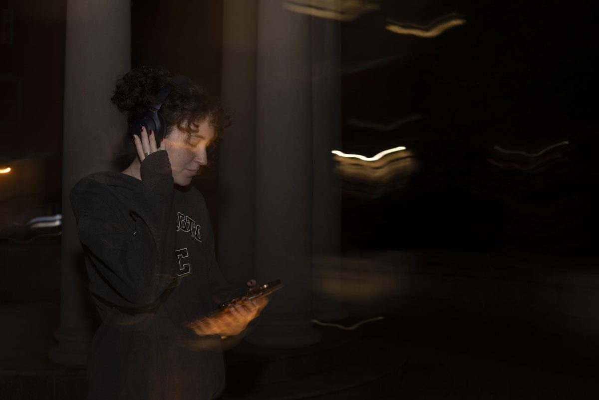 A student locks in to a playlist during a nighttime stroll through Kogan Plaza.
