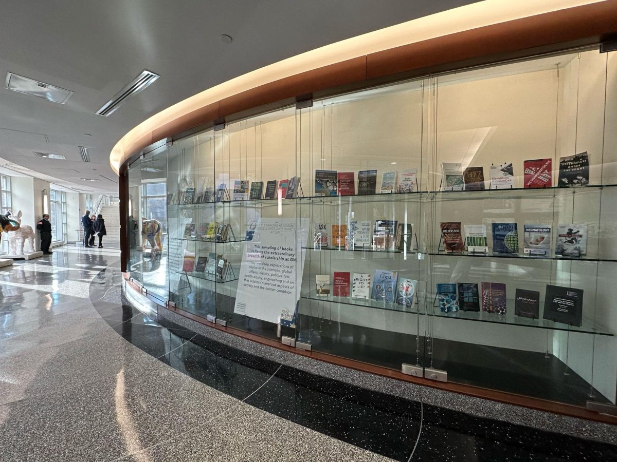 A spread of scholarly literature authored by GW faculty members sits behind panes of glass in the School of Media & Public Affairs.