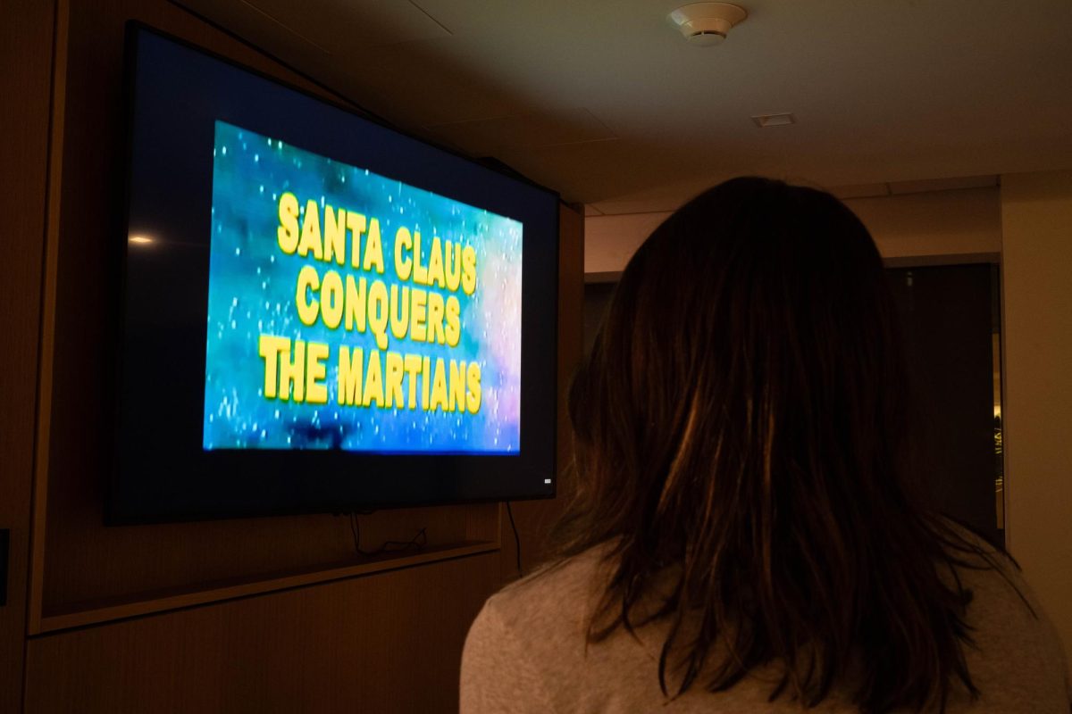 A viewer sits entranced by holiday sci-fi film “Santa Claus Conquers the Martians.