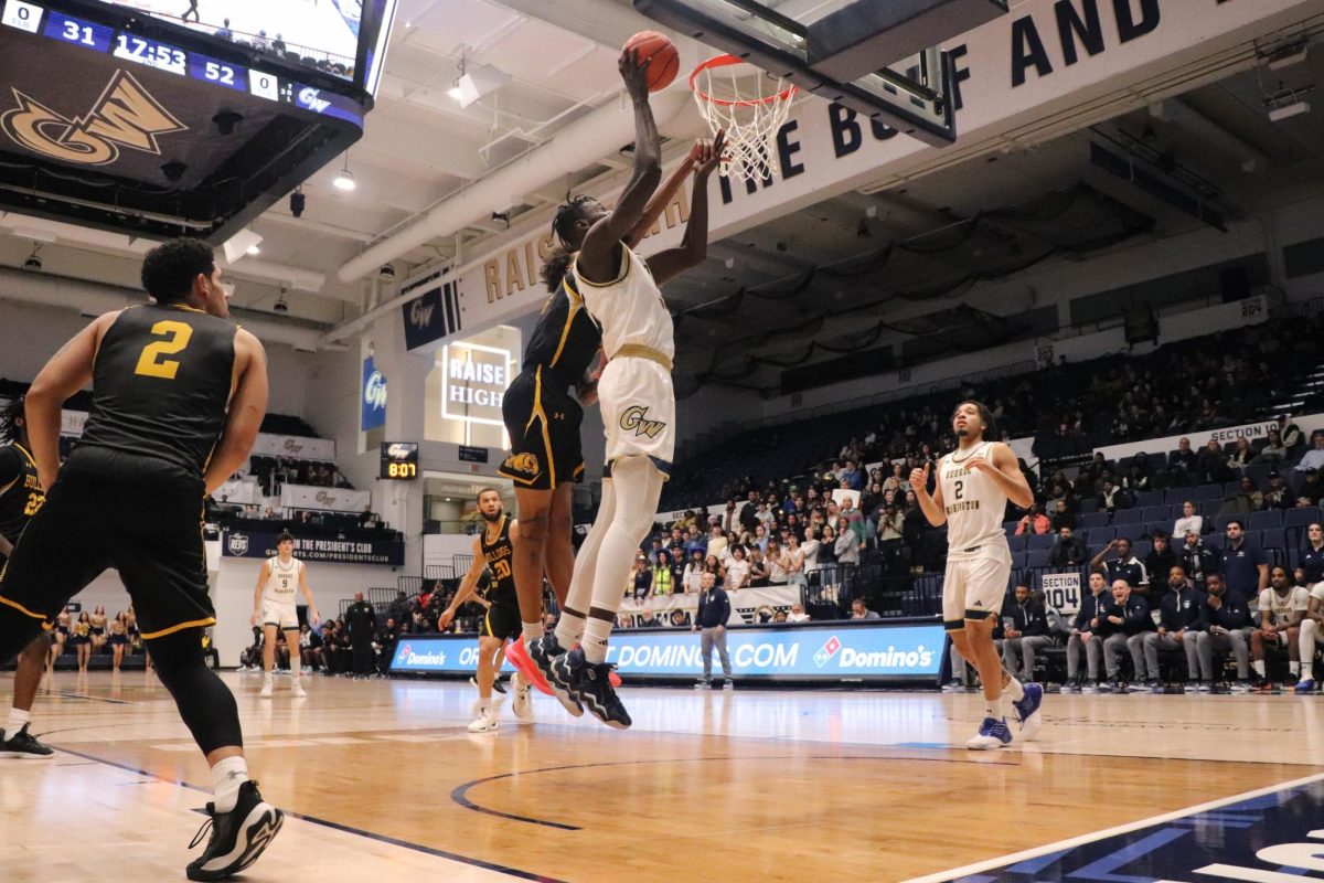 Graduate student center Babatunde Akingbola puts a shot up over the outstretched arms of a defender.
