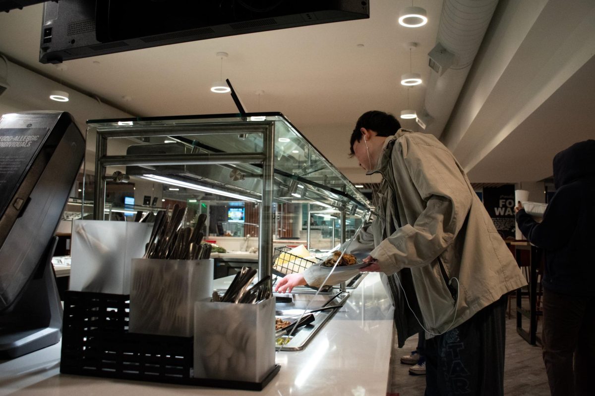 A student reaches for food at the dining hall in Thurston Hall.