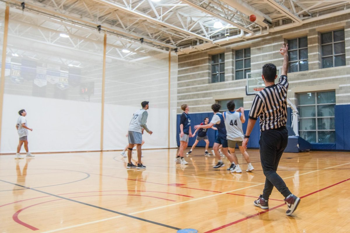 A student referee signals a 3-point attempt during an intramural game in the Lerner Health and Wellness Center. 