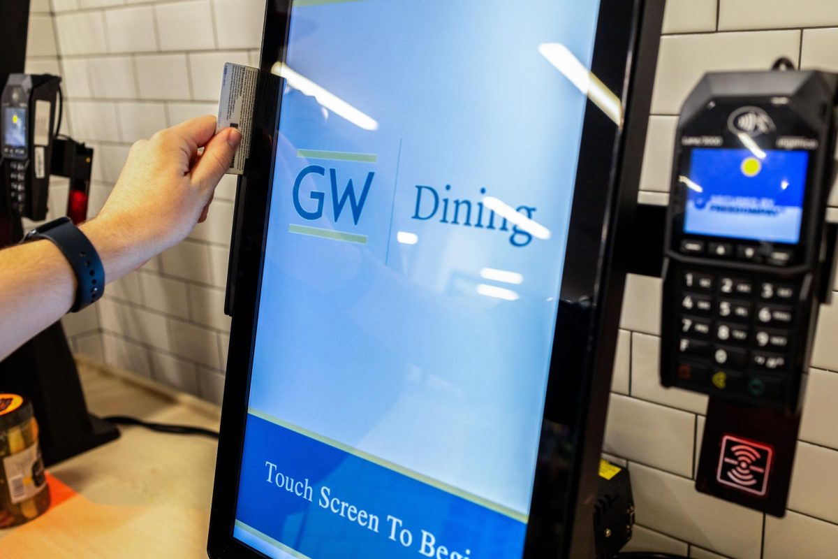 A student swipes their GWorld card at a dining kiosk. 