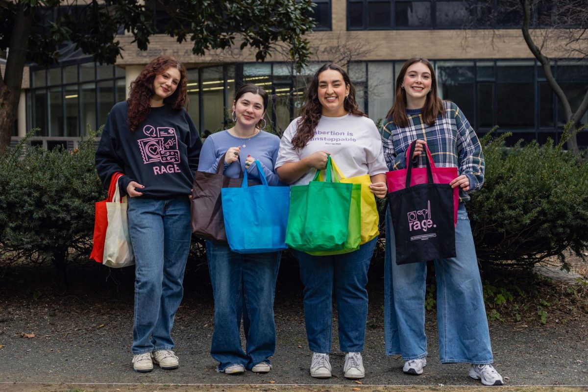Members of GW Reproductive Autonomy and Gender Equity hold “abortion support bags” — fabric tote bags with pads, heating packs and ibuprofen — that doulas will provide to students receiving abortions.