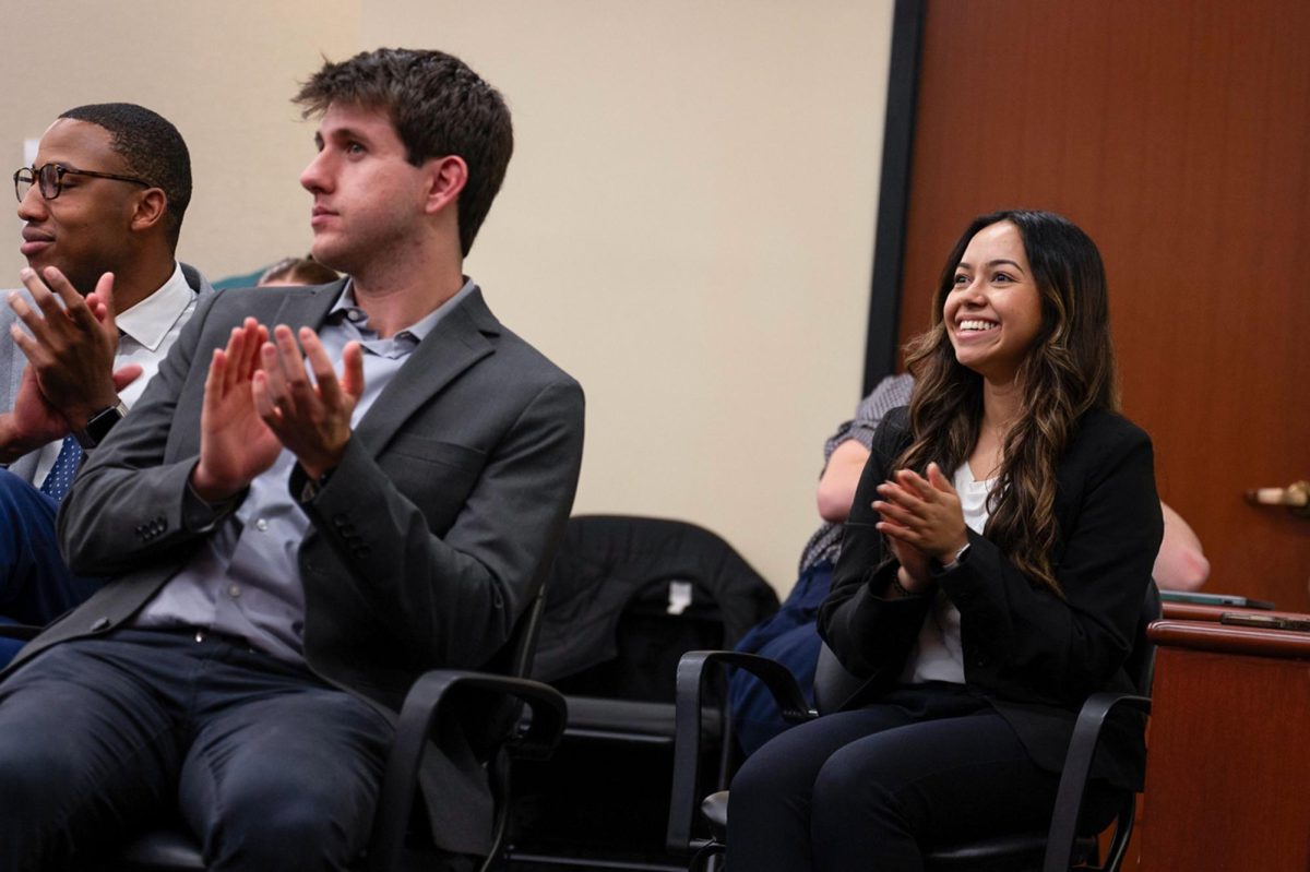 From left to right outgoing Student Bar Association President Shallum Atkinson, Vice President of Finance Spencer Sandusky and incoming President Raisa Shah applaud during Tuesday night's meeting.
