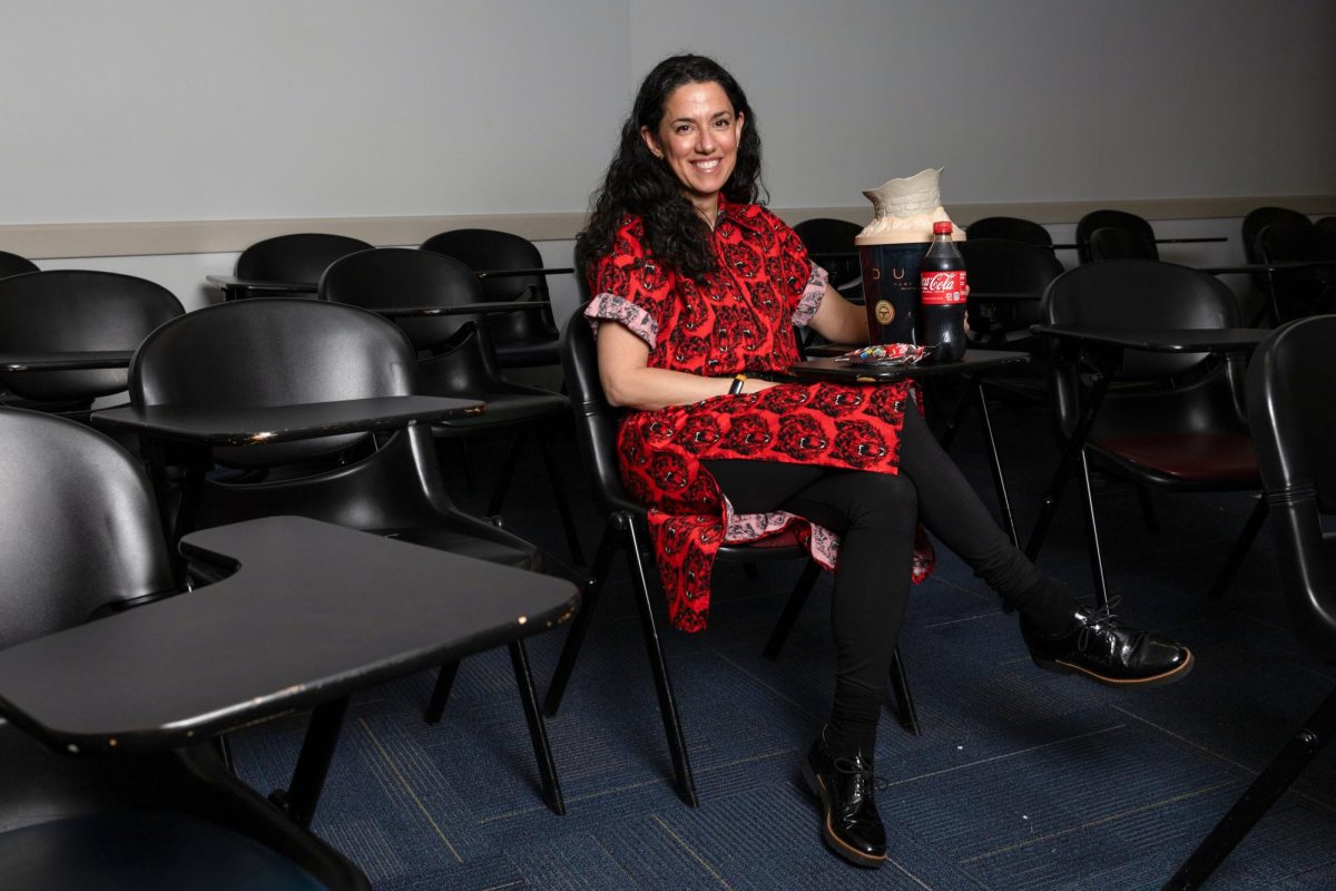 Professor Elisabeth Anker sits with a Dune: Part Two popcorn bucket and other movie snacks. 