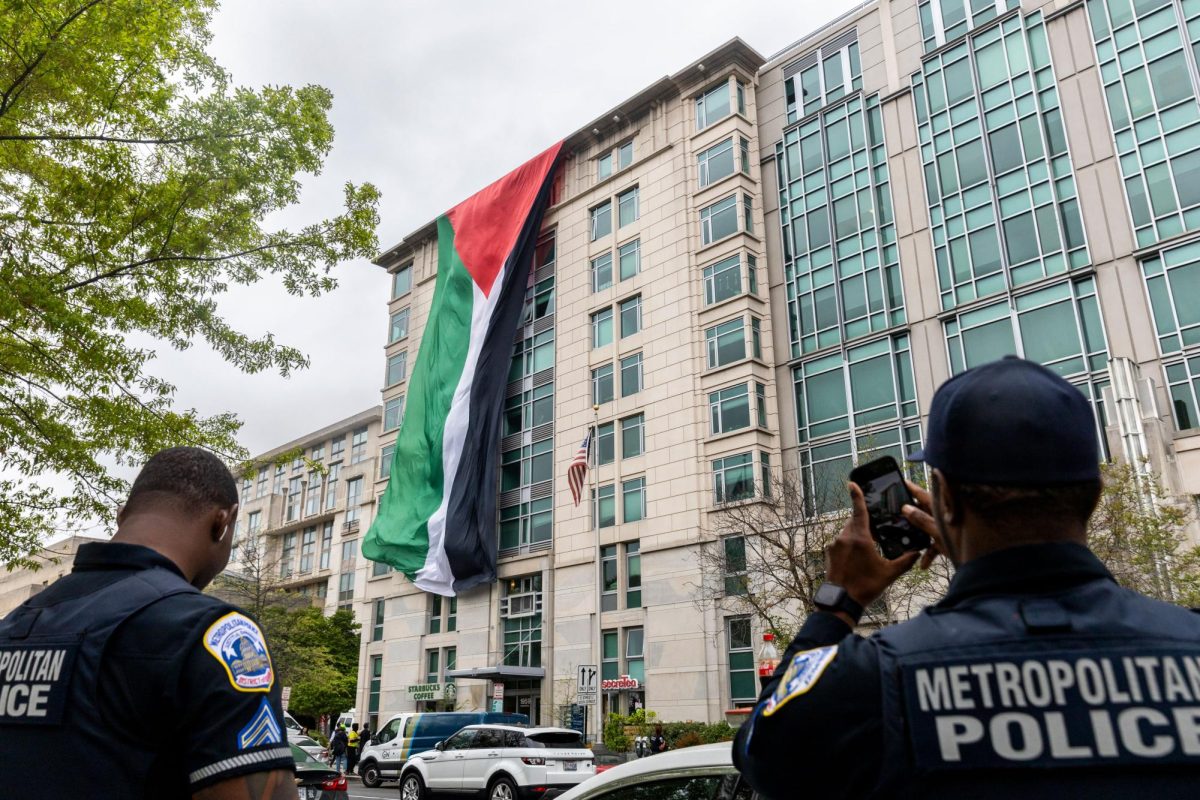 A Metropolitan Police Department officer on scene snaps a photo of a Palestinian flag unfurled from the 1959 E Street roof. 