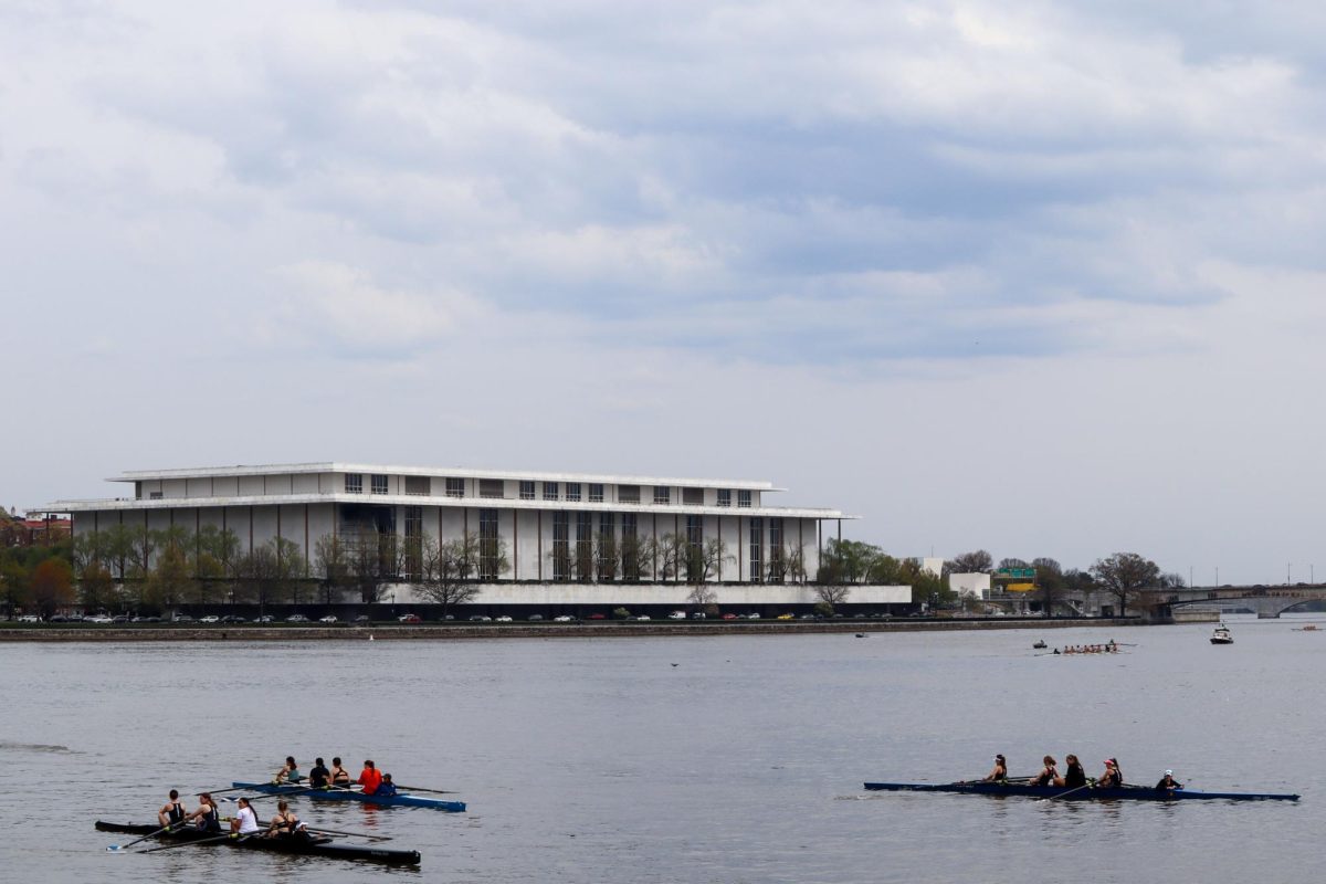 Rowers glide across the Potomac River as The Kennedy Center sits on the horizon.