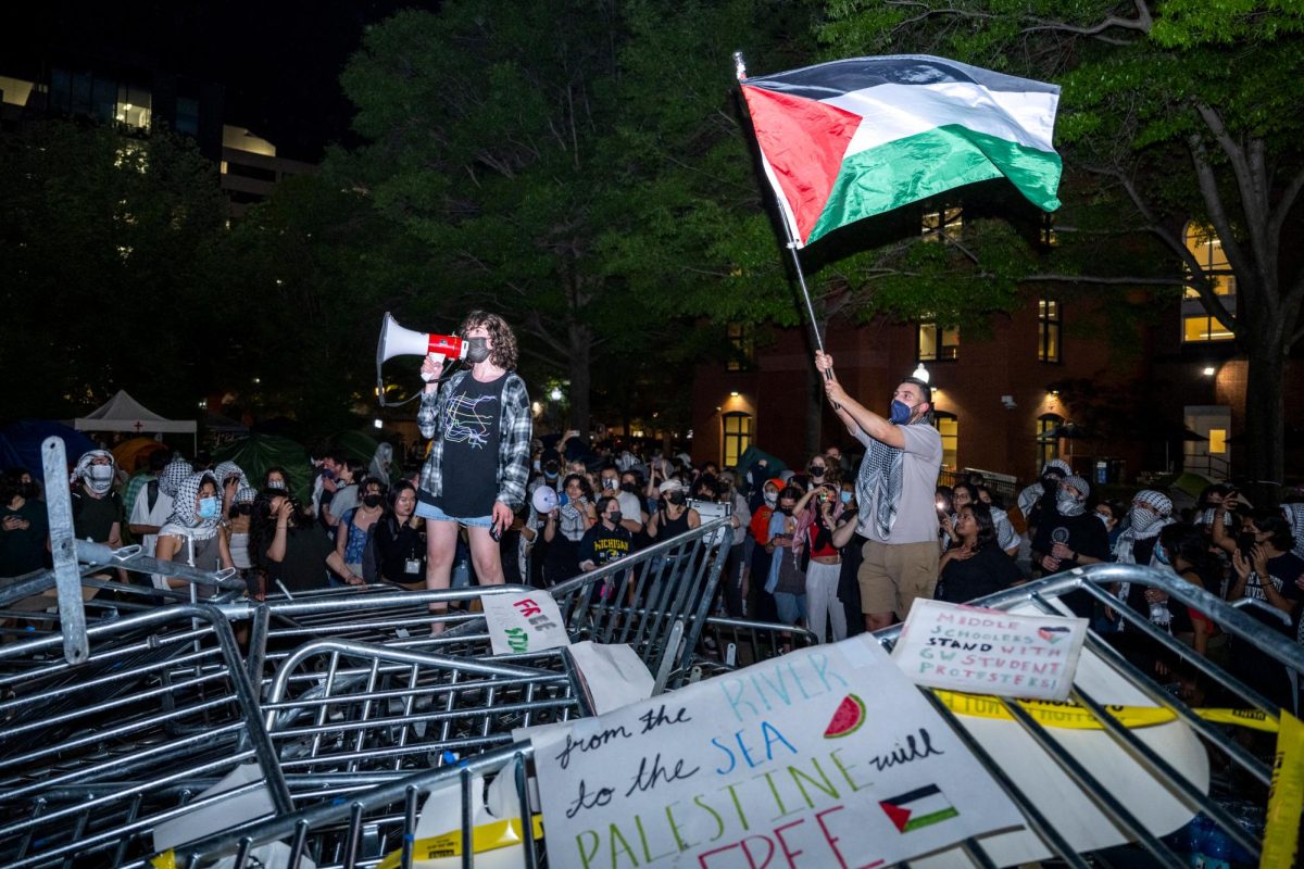 An organizer stands at the top of a mountain of barricades Sunday night while another protester waves a Palestinian flag.