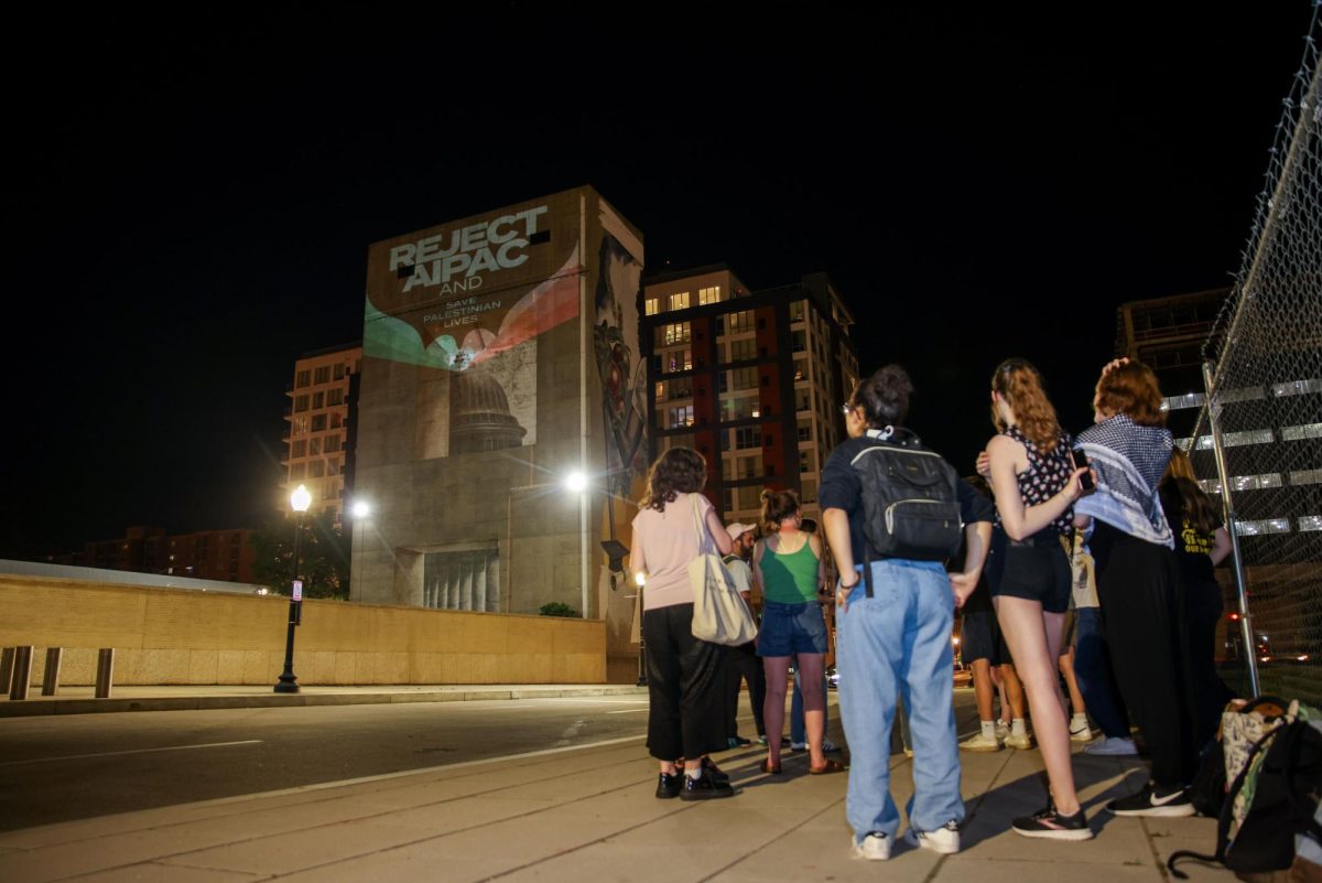 Onlookers observe the pro-Palestinian messages projected across the American Israel Public Affairs Committee building.