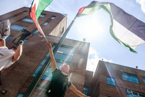 A demonstrator waves a Palestinian flag under the one hoisted on the Lisner Hall flag pole.