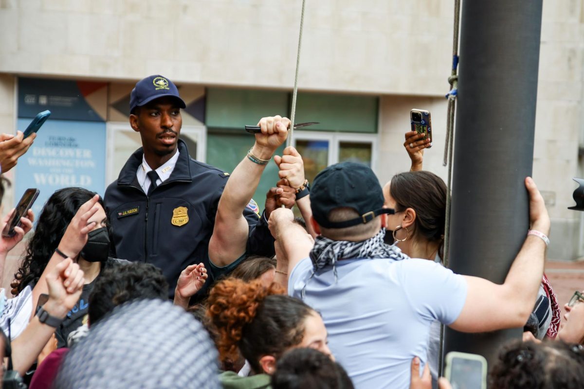 A GW Police Department officer cuts the rope to the Lisner Hall flagpole after protesters attempt to re-hoist a large Palestinian flag.
