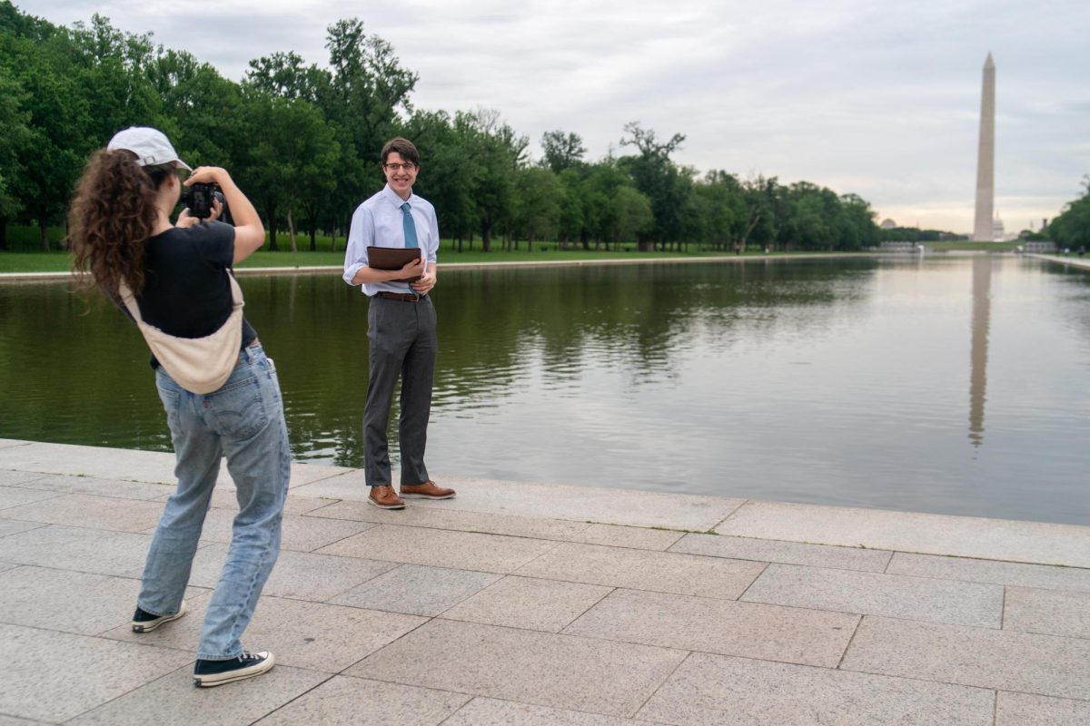 A student photographer takes a graduating students portrait at the Lincoln Memorial Reflecting Pool.