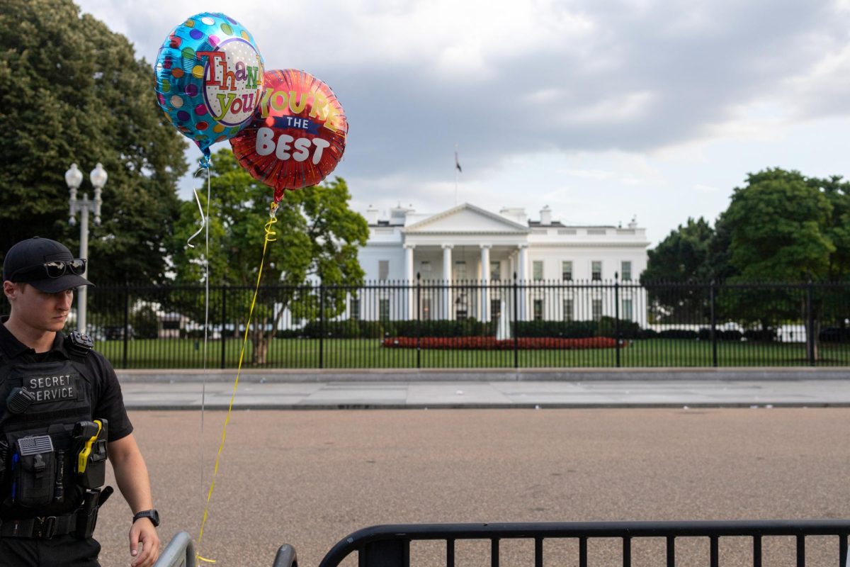 A Secret Service officer moves a gate with celebratory balloons to block 1600 Pennsylvania Avenue.