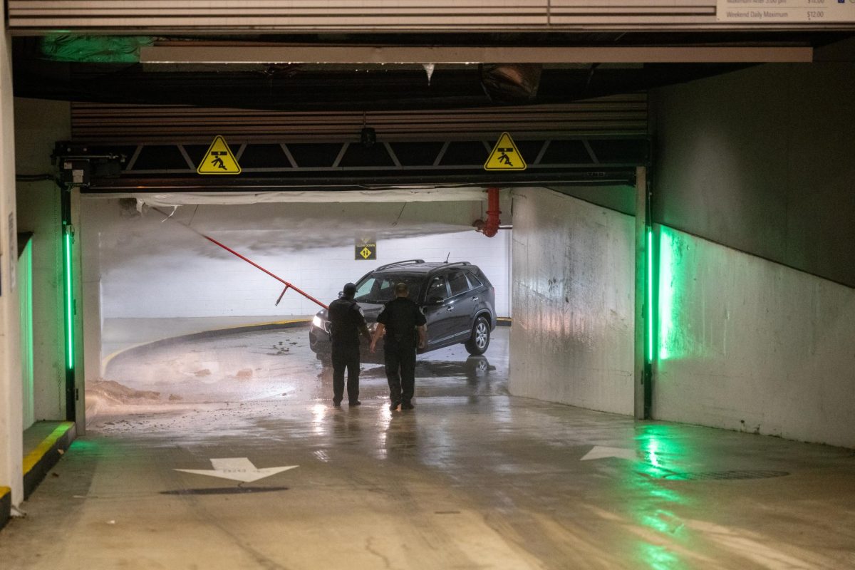 A car drives out of the Science and Engineering Hall parking garage as water flows from a broken fire suppression pipe.