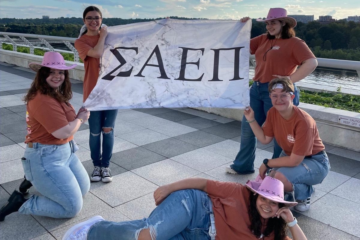 Former members of GW Sigma Alpha Epsilon Pi hold up the sorority's flag.