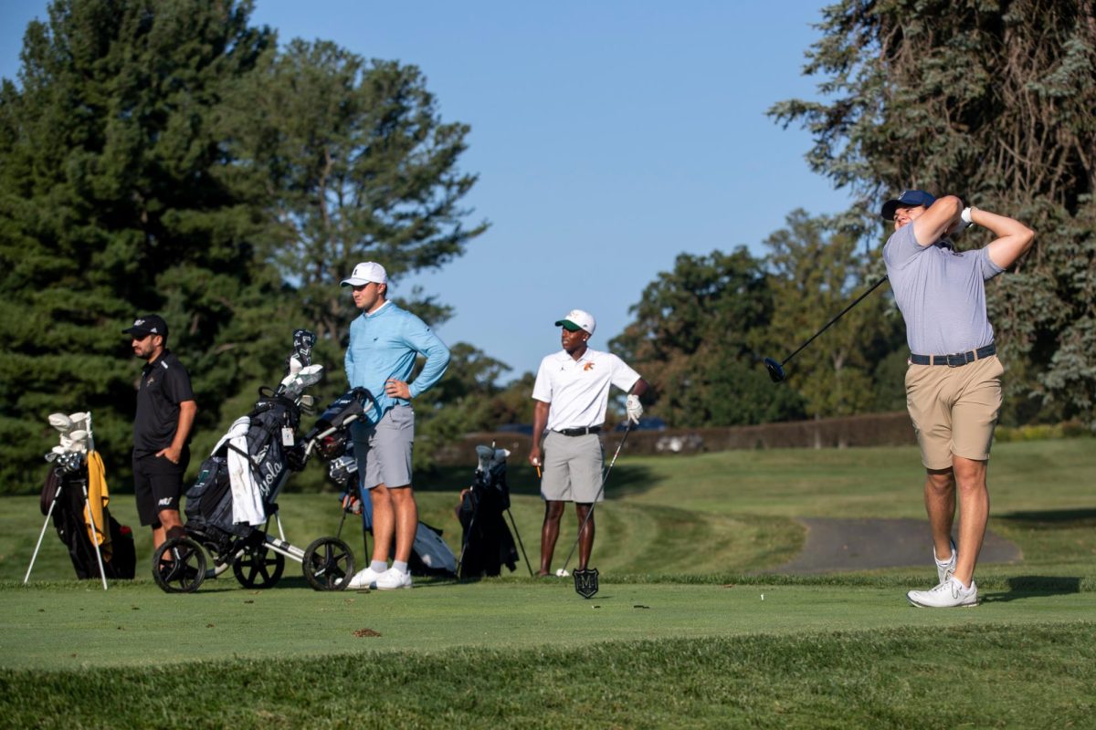 Sophomore Benjamin Garcia Moreira swings from the teeing area as his opponents look on. 