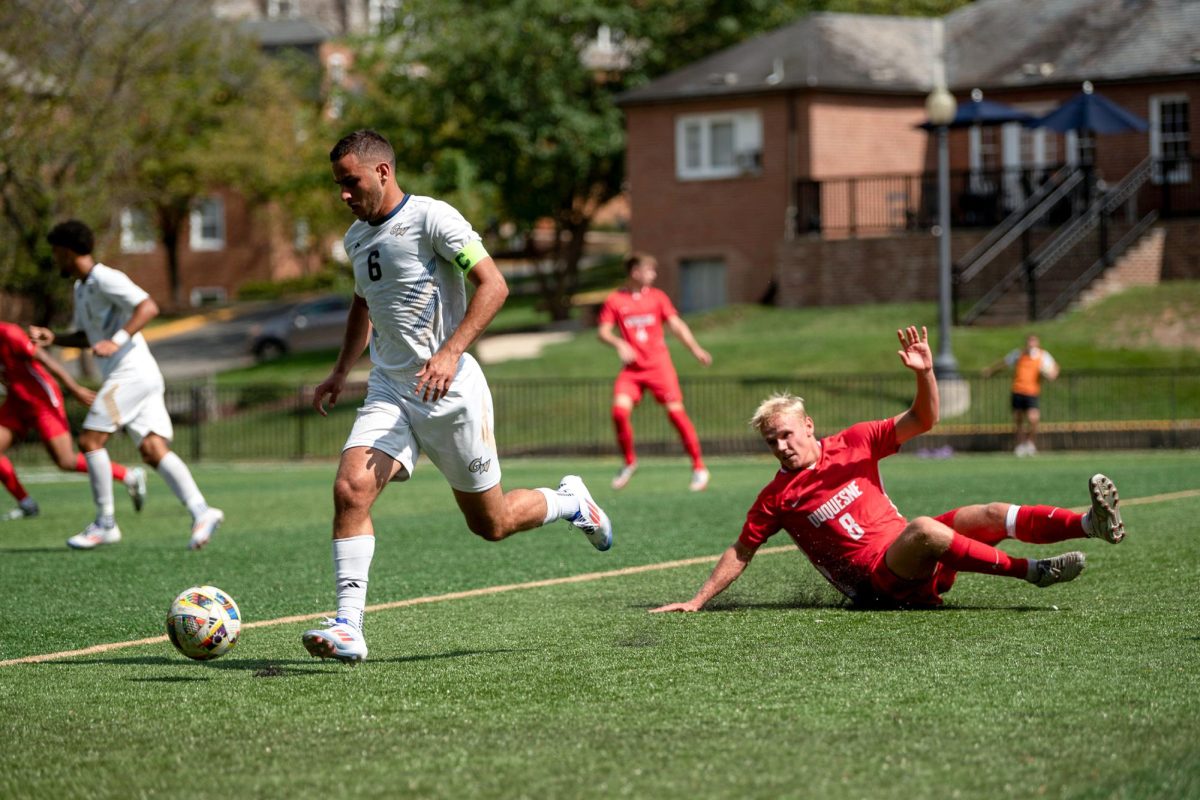 Graduate midfielder Roee Tenne kicks the ball as an opponent from Duquesne University slides.