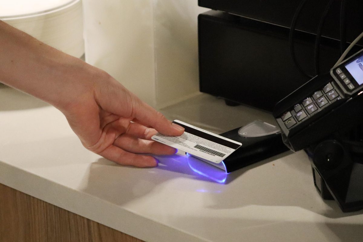 A student taps their GWorld on a new card reader in the Thurston Hall dining hall.