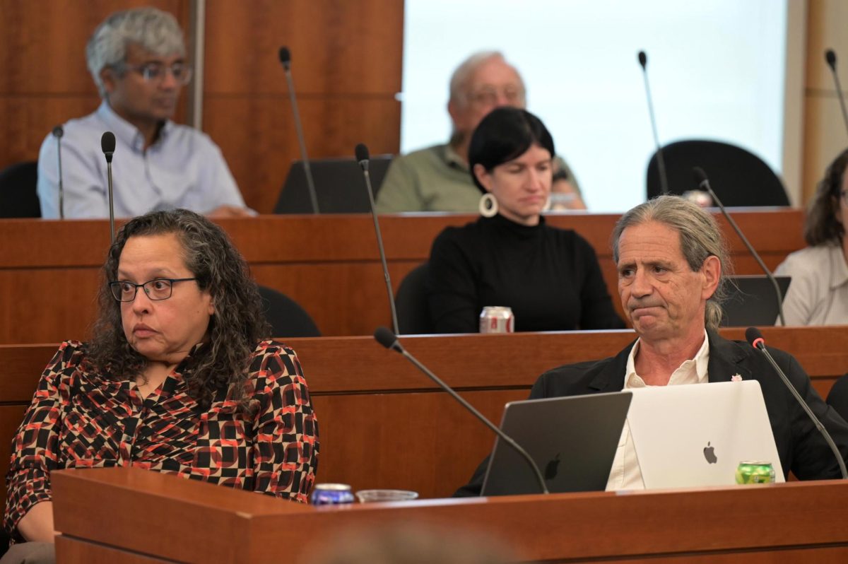 Guillermo Orti, right, and Patricia Hernandez, left, react to discussion about former GW Police Department officers's reports of departmental disarray at a Faculty Senate meeting this month.