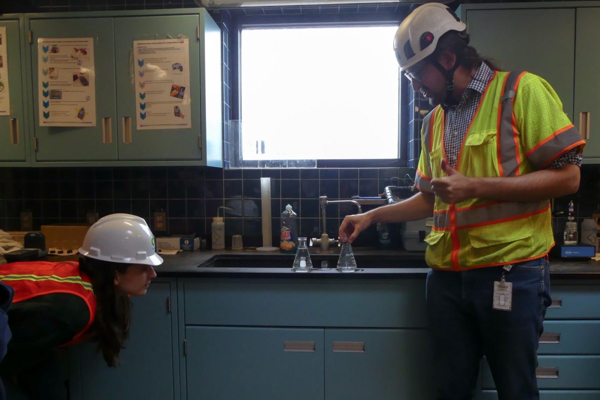 A student peers at two Erlenmeyer flasks, trying to discern which flask contains drinking water and which contains untreated water.