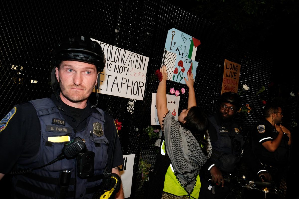 Demonstrators place signs and flowers on the anti-scale fence limiting access to University Yard.